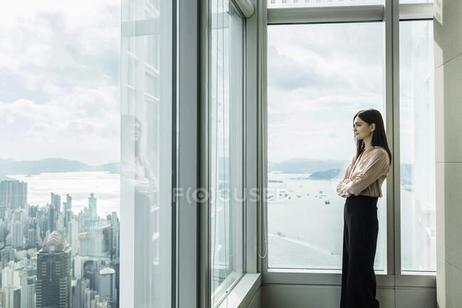 Donna d'affari che guarda fuori dalla finestra al paesaggio urbano — Foto stock