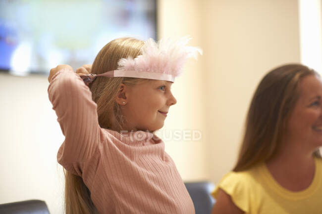 Chica joven poniéndose tiara de plumas - foto de stock