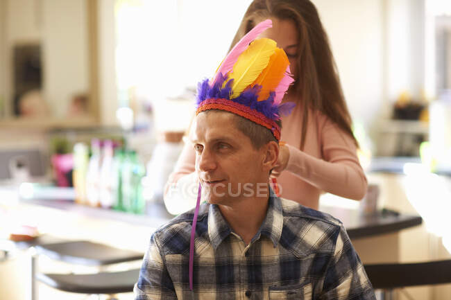 Девушка надевает шляпу с перьями на отца — стоковое фото