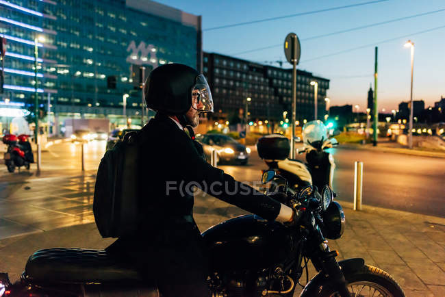 Maduro hombre de negocios a caballo en motocicleta por la noche - foto de stock