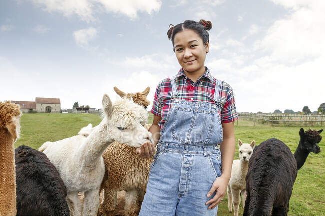 Portrait of woman with alpacas on farm — Stock Photo