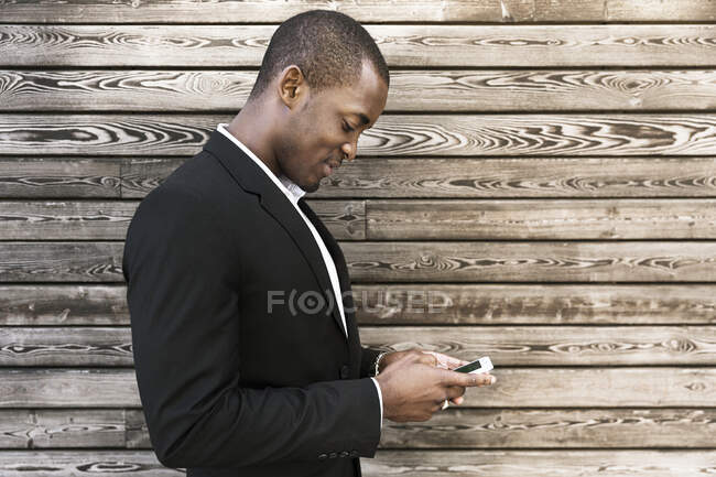 Людина використовує мобільний телефон на дерев'яній панелі — стокове фото