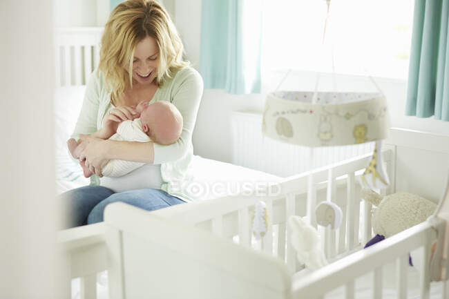 Mutter sitzt auf Bett und hält neugeborenes Baby — Stockfoto