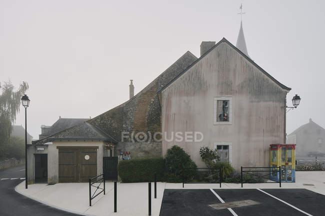 Casa a dos aguas y estacionamiento en Meigne-le-Vicomte pueblo en la mañana brumosa, Valle del Loira, Francia - foto de stock