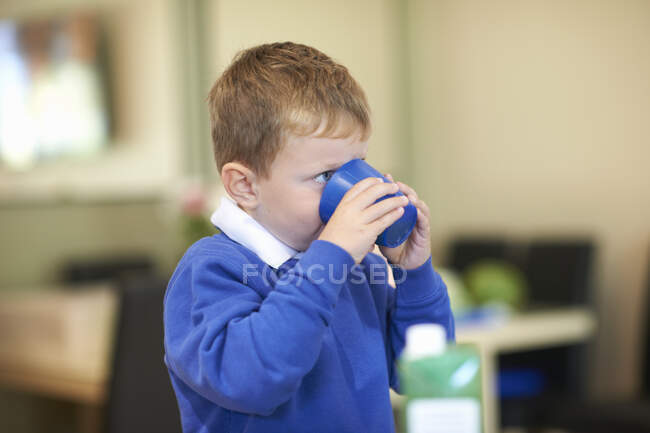 Schoolboy beber suco na cozinha — Fotografia de Stock