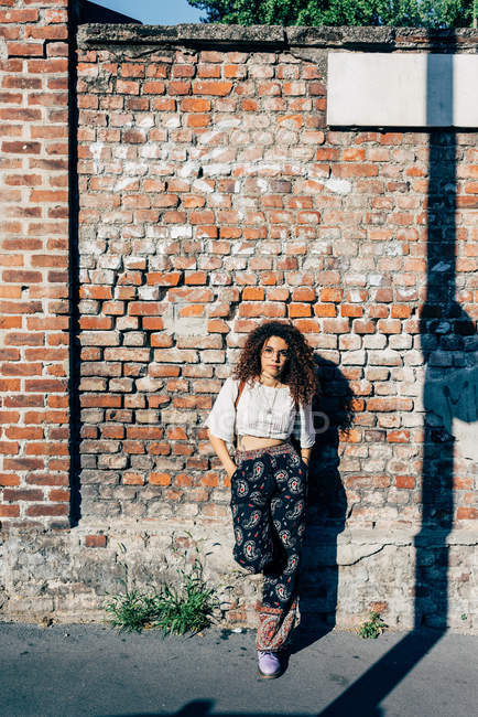 Молода жінка позує на цегляну стіну — стокове фото