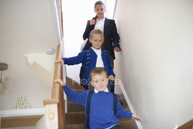 Teenager Schulmädchen mit Schwester und Bruder in Uniformen bewegen sich die Treppe hinunter — Stockfoto