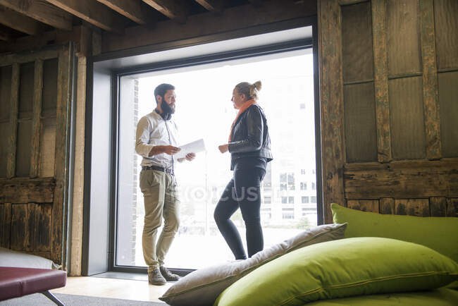Colleagues standing by window chatting — Stock Photo