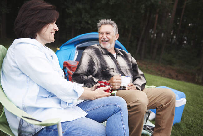 Mature couple sitting in camping chairs with cups of tea — Stock Photo