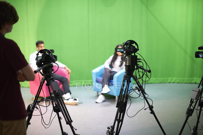 Jóvenes estudiantes universitarios que practican en un estudio de televisión con pantalla verde - foto de stock