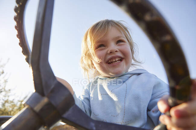 Young girl holding tractor's steering wheel, low angle view — Stock Photo
