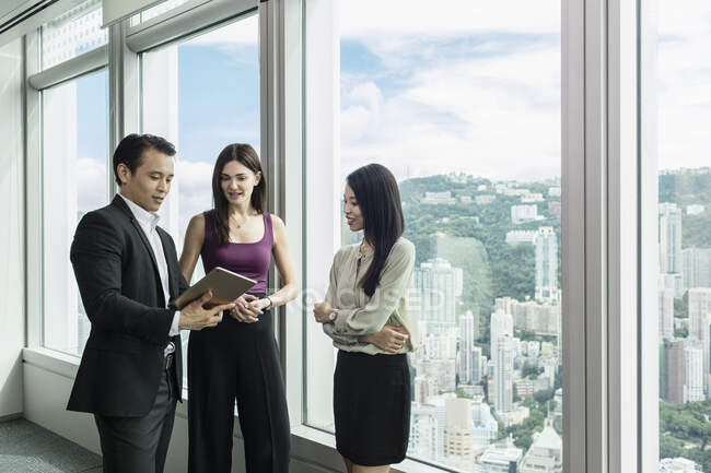 Colleagues with digital tablet standing chatting — Stock Photo