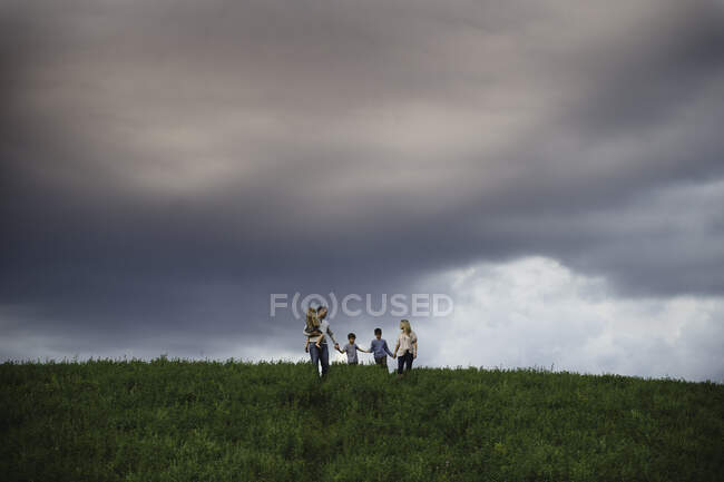 Famille de cinq personnes profitant du plein air sur un terrain herbeux vert — Photo de stock