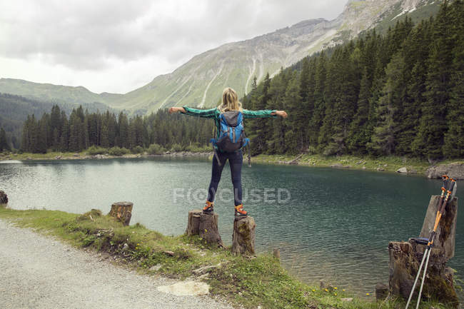 Vue arrière d'une femme se balançant sur des rochers au bord d'un lac, Tyrol, Steiermark, Autriche, Europe — Photo de stock