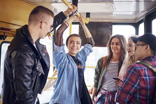 Cinco amigos adultos jóvenes charlando en el tranvía de la ciudad - foto de stock