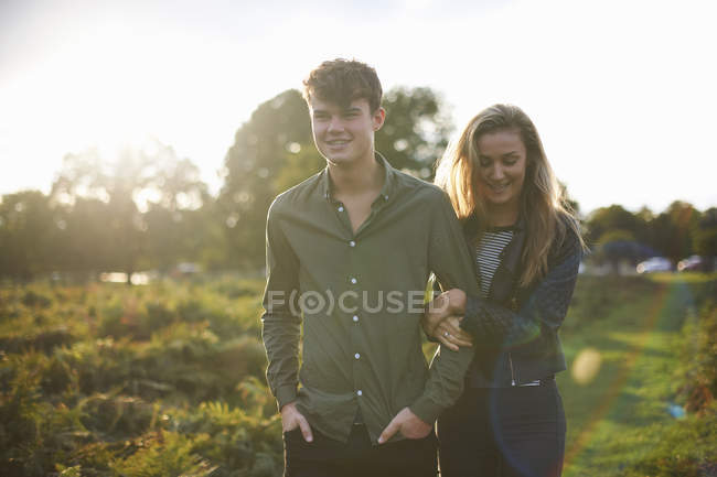 Jovem casal passeando braço a braço no campo — Fotografia de Stock