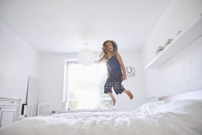Junges Mädchen springt auf dem Bett, Blick in den niedrigen Winkel — Stockfoto