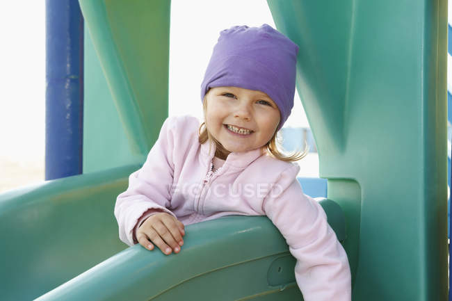 Retrato de menina no slide olhando para a câmera e sorrindo — Fotografia de Stock