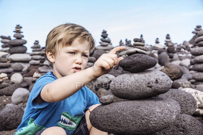 Jeune garçon examinant une pile de roches, Santa Cruz de Tenerife, Îles Canaries, Espagne, Europe — Photo de stock