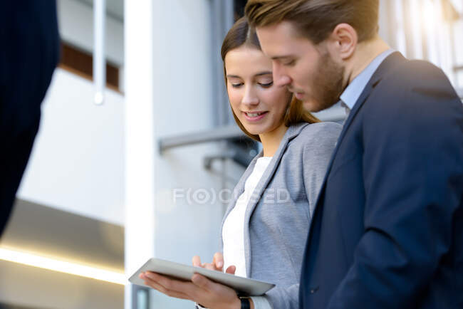 Молода бізнес-леді і чоловік, використовуючи цифровий планшетний сенсорний екран в офісному атріумі — стокове фото