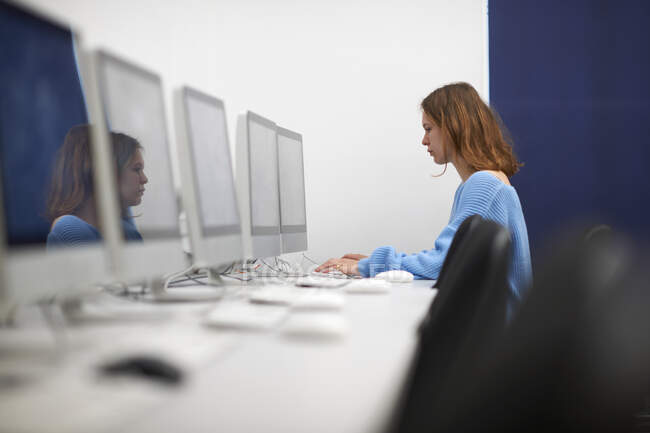 Young female college student typing on computer keyboard in classroom — Stock Photo