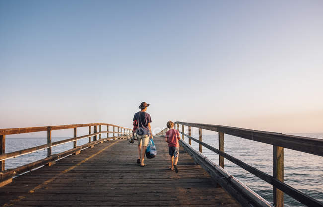 Rear view of father and son walking on pier, Goleta, California, United States, North America — Stock Photo
