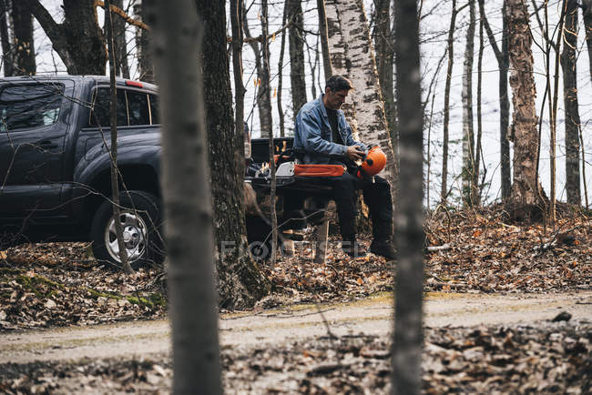 Holzfäller sitzt auf Pick-up-Truck und hält harten Hut — Stockfoto