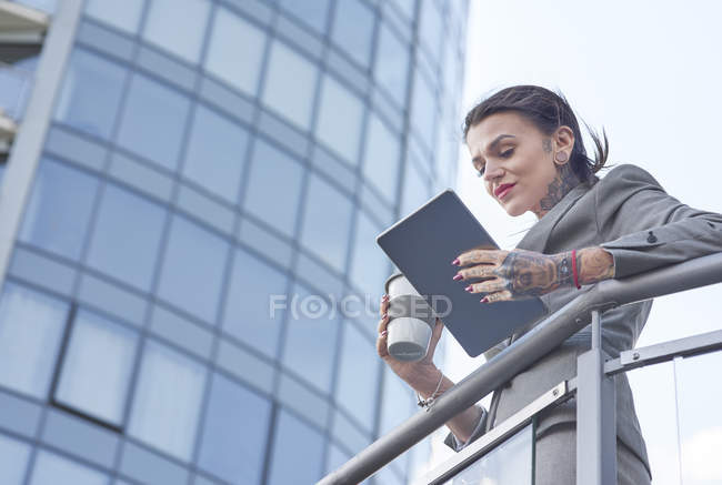 Businesswoman holding coffee cup and digital tablet outdoors — Stock Photo