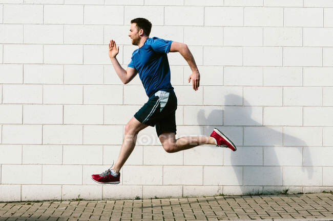 Giovane velocità corridore maschile che corre lungo il marciapiede — Foto stock