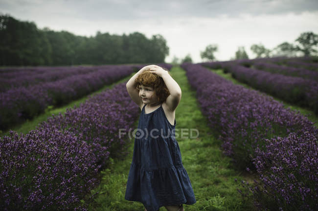 Petite fille debout entre les rangées de lavande — Photo de stock