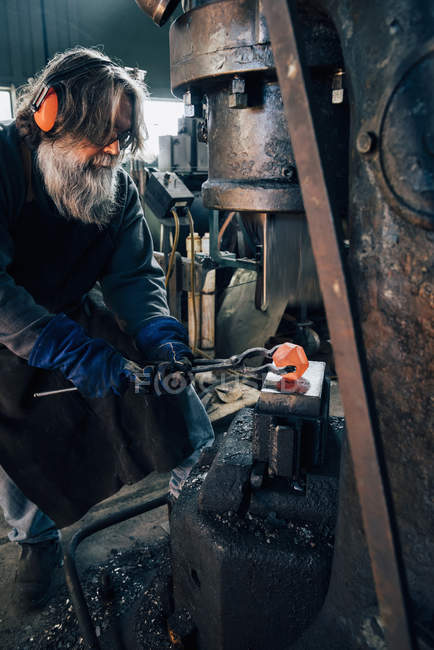 Blacksmith using blacksmith tongs for red hot metal — Stock Photo