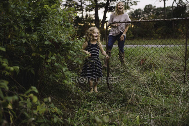 Madre e hija entrando puerta de granja - foto de stock