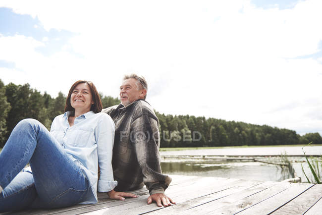 Mature couple relaxing on pier beside lake — Stock Photo