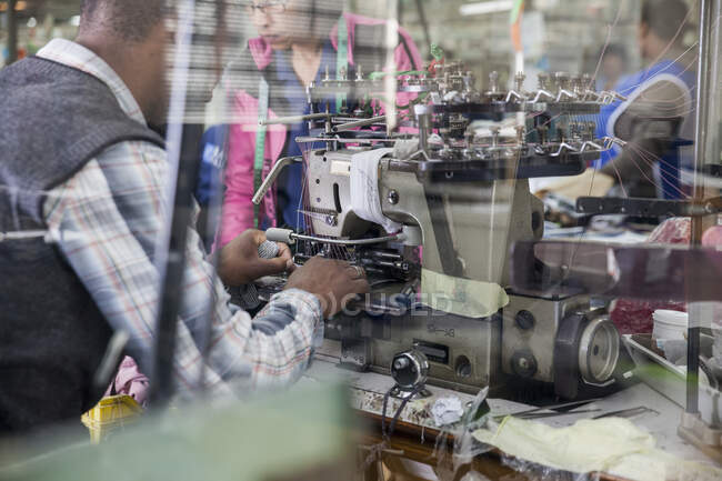 Hombre de mantenimiento que trabaja en la máquina de coser de smocking industrial, Ciudad del Cabo, Sudáfrica - foto de stock