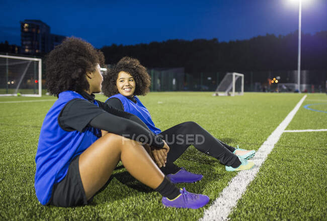 Jugadoras de fútbol sentadas por campo, Hackney, East London, Reino Unido - foto de stock