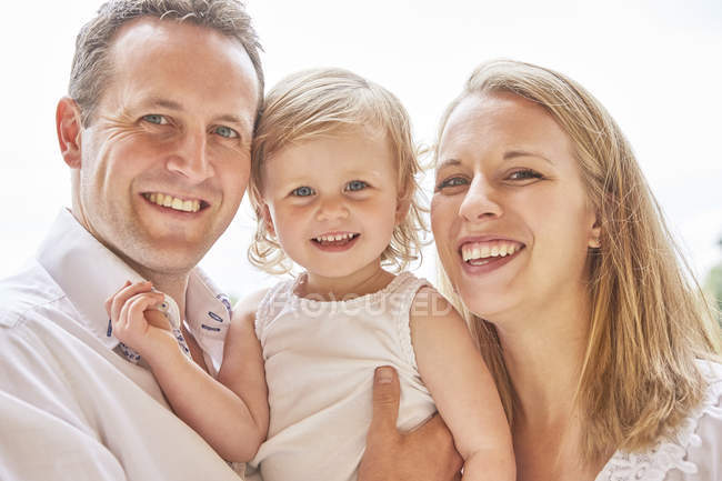 Portrait of couple with baby daughter smiling at camera — Stock Photo