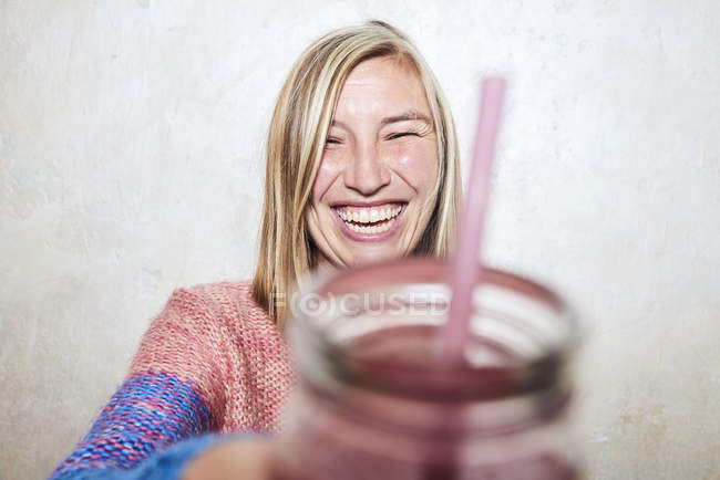 Портрет женщины, держащей напиток перед камерой, смеющейся — стоковое фото