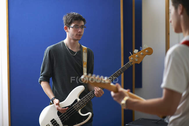 Young male college students playing guitars in recording studio — Stock Photo