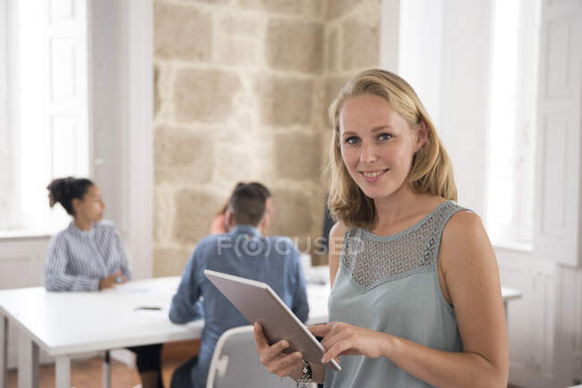 Retrato de jovem empresária segurando tablet digital no escritório — Fotografia de Stock