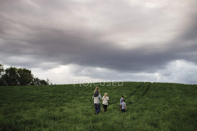 Famille de cinq personnes profitant du plein air sur un terrain herbeux vert — Photo de stock