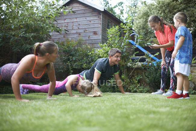 Família exercitando e fazendo flexões no jardim — Fotografia de Stock