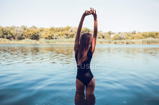 Вид сзади на женщину в купальнике, стоящую в воде — стоковое фото
