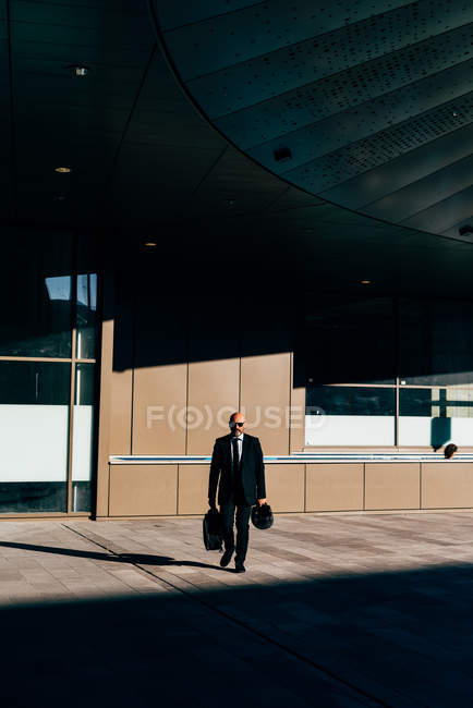 Mature businessman carrying bag and motorcycle helmet outdoors — Stock Photo