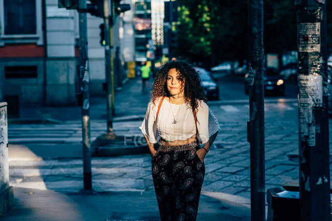 Женщина, стоящая в тени у дороги, Милан, Италия — стоковое фото