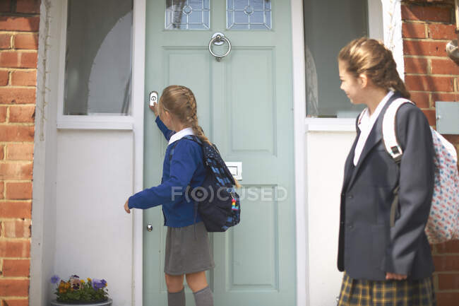 Escola menina e adolescente irmã fechando porta da frente — Fotografia de Stock