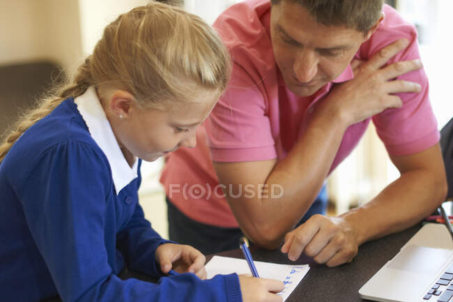 Pai ajudando filha com lição de casa no balcão da cozinha — Fotografia de Stock