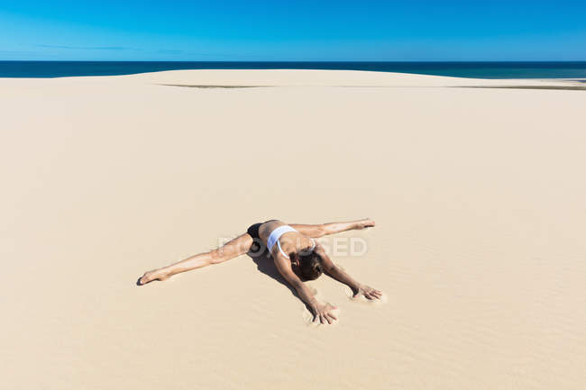 Woman on sandy beach in yoga position — Stock Photo