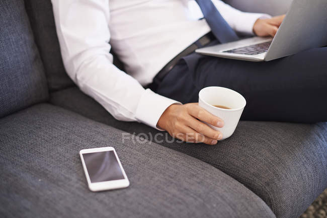 Середина бізнесмена, що використовує ноутбук на дивані — стокове фото