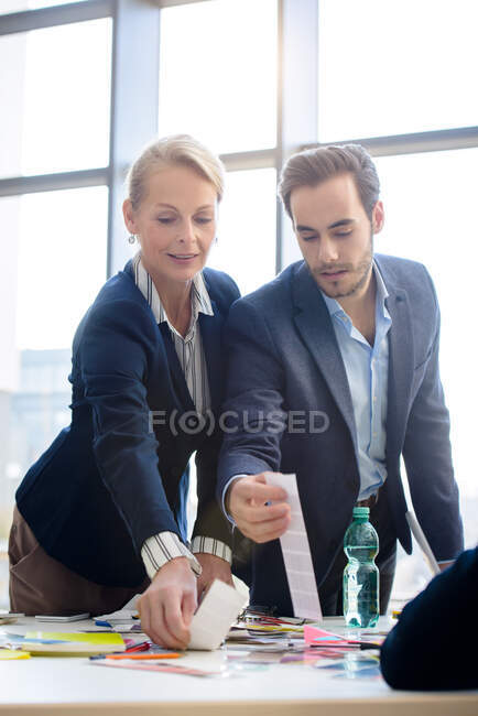 Businesswoman and man selecting swatches from boardroom table — Stock Photo