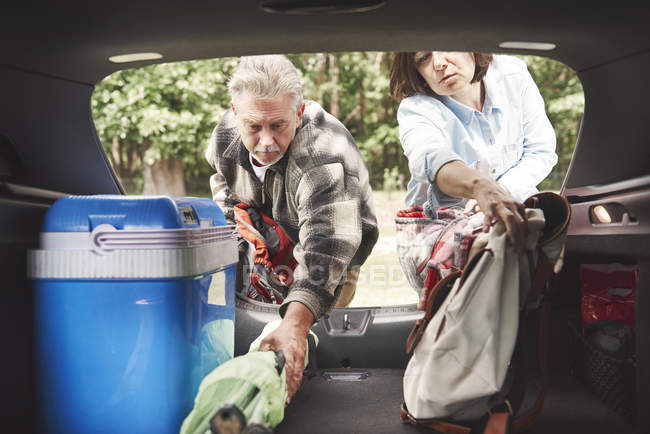 Couple d'âge mûr enlever l'équipement de camping du coffre de voiture — Photo de stock